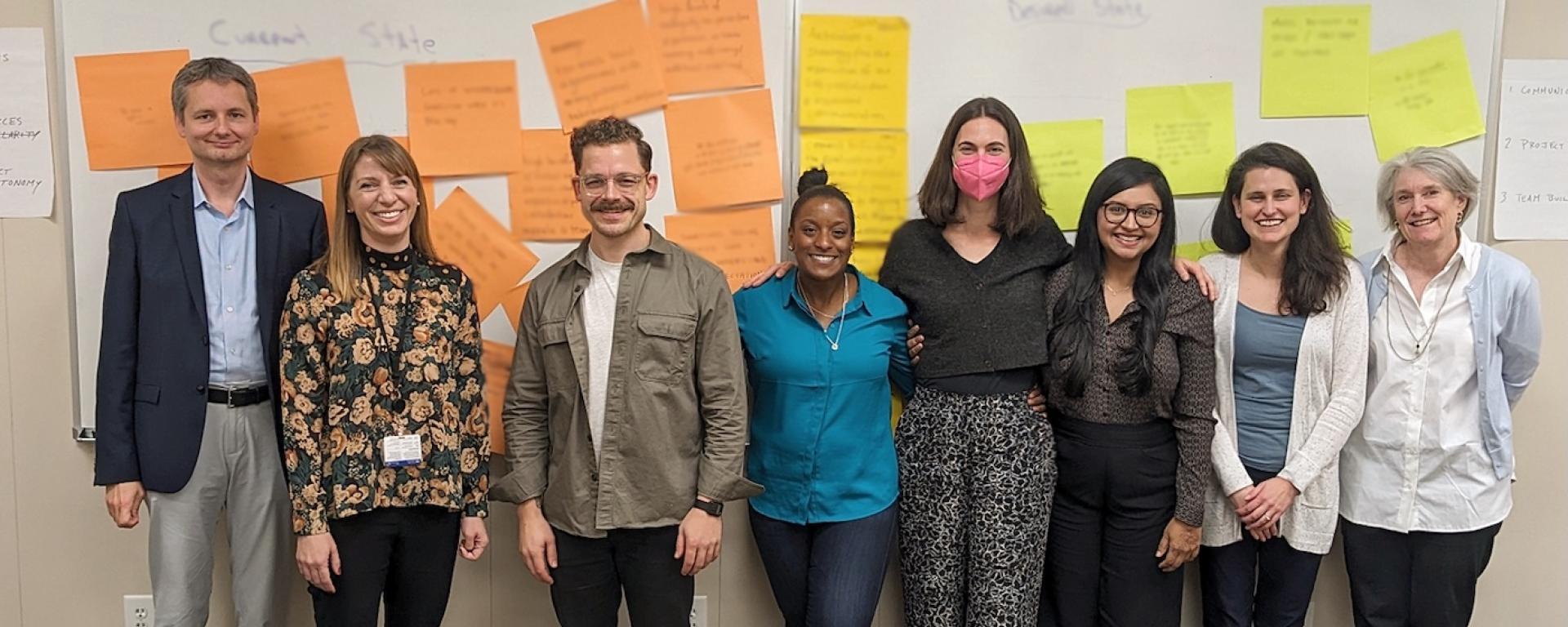 Image showing the Duke Health AI E&G team standing up against a wall full of post-its.