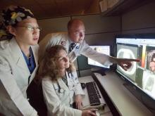Three medical professionals reviewing and analyzing diagnostic imaging on monitors.